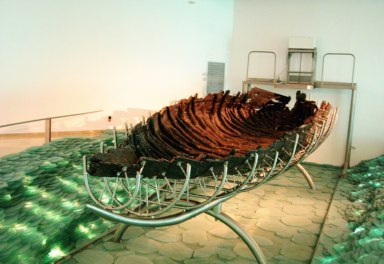 Surviving dark wooden hull of the Sea of Galilee boat resting on a modern metal conservation frame.