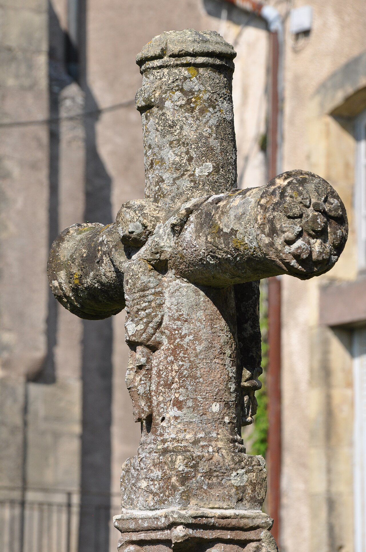 Weathered stone cross outside the abbey church in Faverney